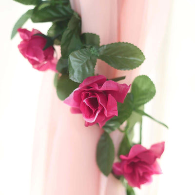 Pink artificial roses with green leaves on a light background.