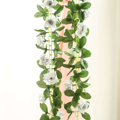 Artificial white rose garland with green leaves on a plain background.