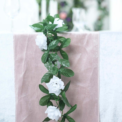 White rose garland on a soft fabric table runner.