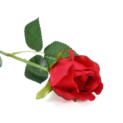 Red artificial rose with green leaves on a white background