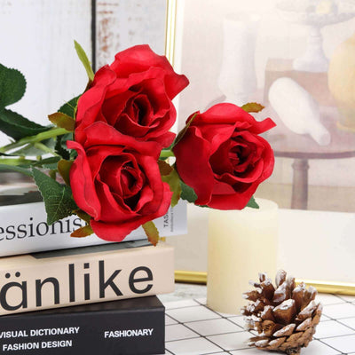 Red artificial roses in a decorative arrangement on stacked books.