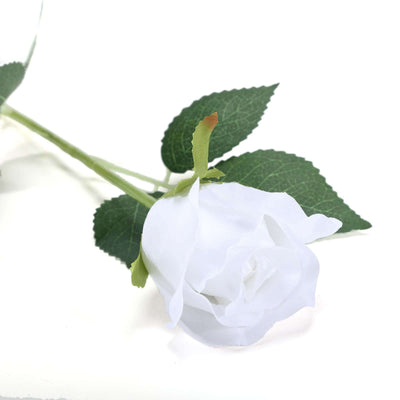 White artificial rose with green leaves on a plain background.