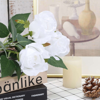 White roses bouquet with green leaves on a decorative table.