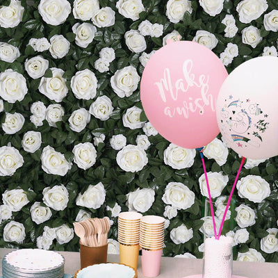 Party setup with pink balloons and tableware against a floral backdrop.