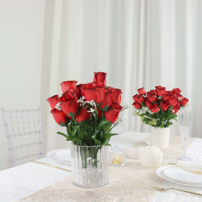 Red roses in elegant vases on a beautifully set dining table.