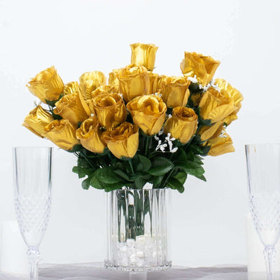 Yellow artificial roses in a clear vase with decorative stones.