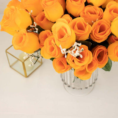 Bright orange artificial roses in a clear vase with decorative accents.