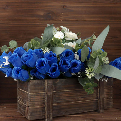 Blue artificial roses in a wooden box with greenery.