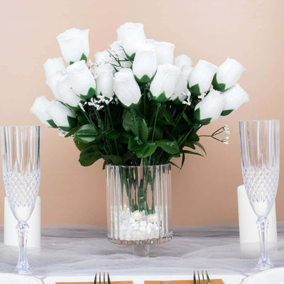 White artificial rose bouquet in a clear vase with decorative stones.