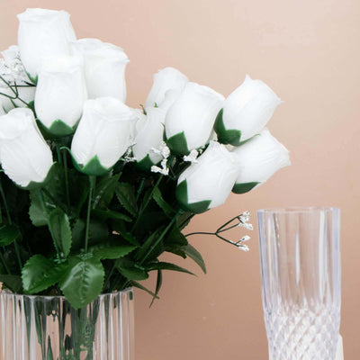 Artificial white roses in a clear vase with a crystal glass.