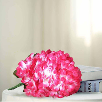Pink hydrangea bouquet on a table next to books.