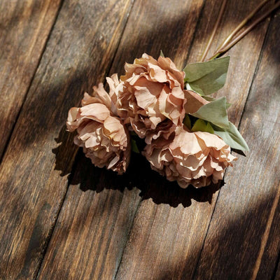 Peach-colored artificial flowers on a wooden surface.