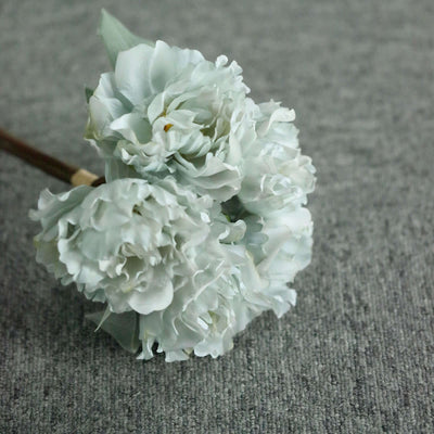 Light blue artificial flowers bouquet on gray fabric background.