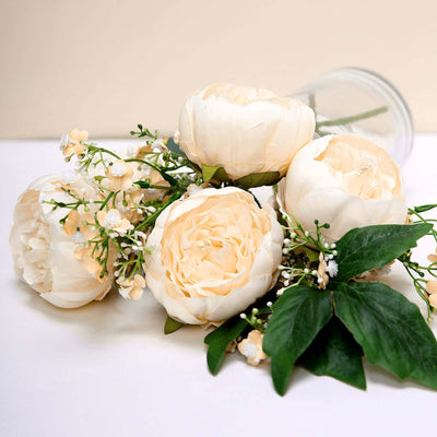 Cream peony bouquet with greenery in a clear vase