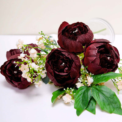 Artificial burgundy peony bouquet with greenery and white flowers.