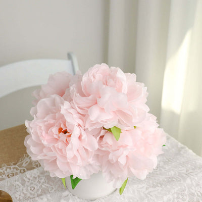 Pink peony bouquet in a white vase on a lace tablecloth.