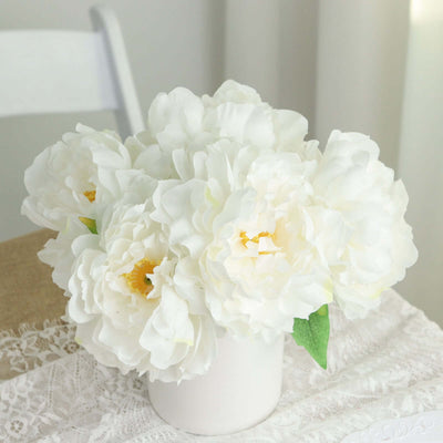 White peony flower bouquet in a white vase on a table.