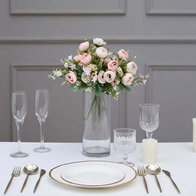 Elegant floral arrangement in a glass vase on a dining table setting.