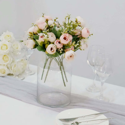 Bouquet of pink roses and white flowers in a clear vase on a dining table.