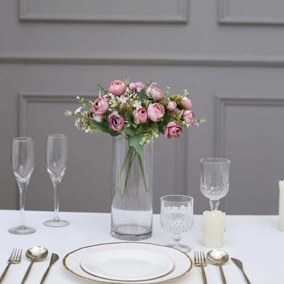 Elegant pink rose bouquet in a glass vase on a dining table setting.