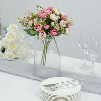 Floral centerpiece with pink roses in a clear vase on a dining table.