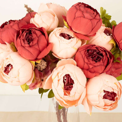 Colorful peony bouquet with shades of red and pink in a clear vase.