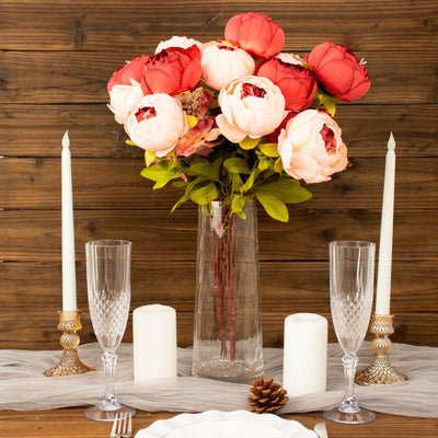 Elegant floral arrangement in a glass vase with candles on a rustic wooden table.