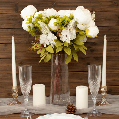 Elegant floral arrangement with candles on a rustic table setting.