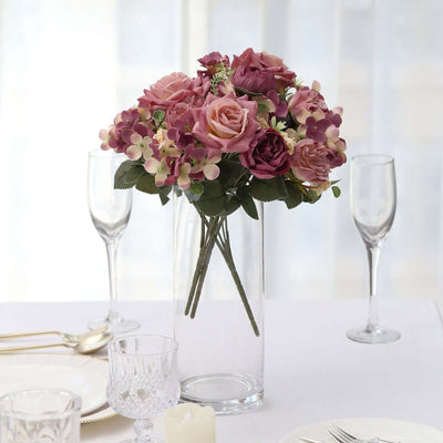 Elegant pink and purple flower bouquet in a glass vase on a dining table.
