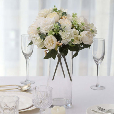 Artificial white flower bouquet in a clear vase on a dining table.