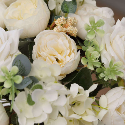 White floral arrangement with roses and greenery in a close-up shot.