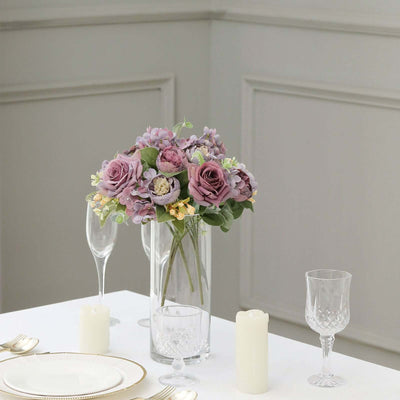 Purple floral bouquet in a glass vase on a dining table.