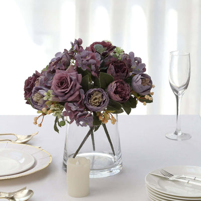Purple floral arrangement in a glass vase on a dining table.