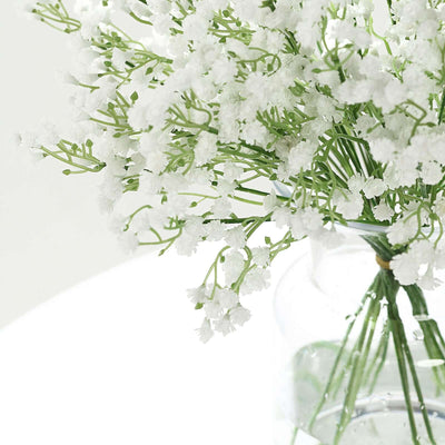 White floral bouquet in a clear vase with green stems.