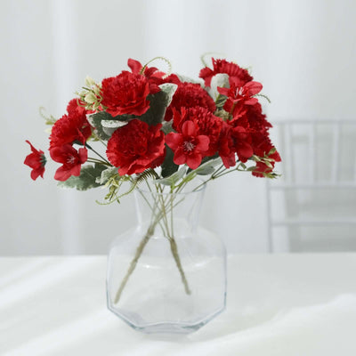 Red floral arrangement in a clear vase on a white table.
