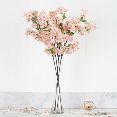 Pink floral arrangement in a modern vase on a marble surface.