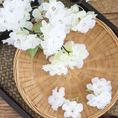 White artificial flowers arranged on a woven tray.