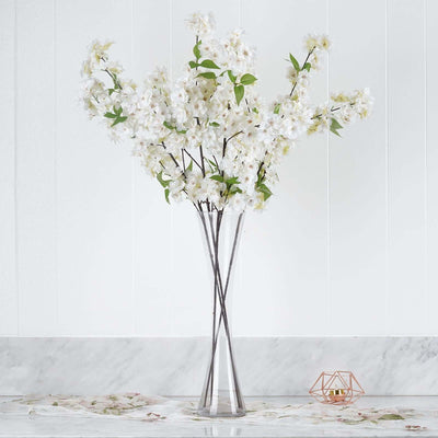 White floral arrangement in a clear vase on a marble countertop.