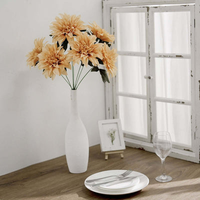 Decorative faux flowers in a vase on a dining table with a window backdrop.