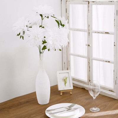 White faux flower arrangement in a vase on a wooden table.