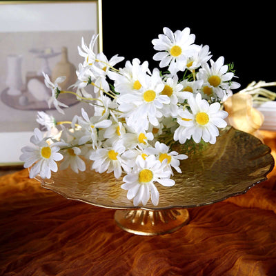 Gold pedestal dish with white daisies arranged artistically.