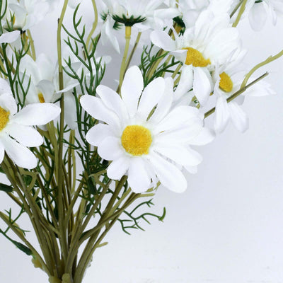 Artificial white daisies bouquet with yellow centers on a white background.
