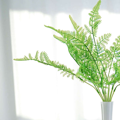 Green artificial fern branches in a modern white vase.
