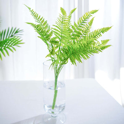 Vibrant green fern arrangement in a clear vase with water.