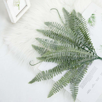 Artificial green fern leaves on a textured background.