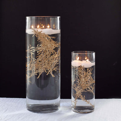 Elegant glass candle holders with floating candles and decorative dried foliage.