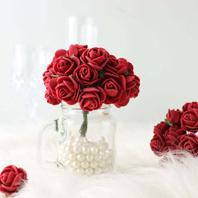 Red rose bouquet in glass jar with pearls on a soft white surface.