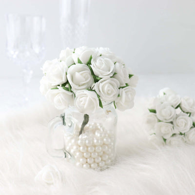 White rose bouquet in a glass jar filled with pearls on a soft surface.