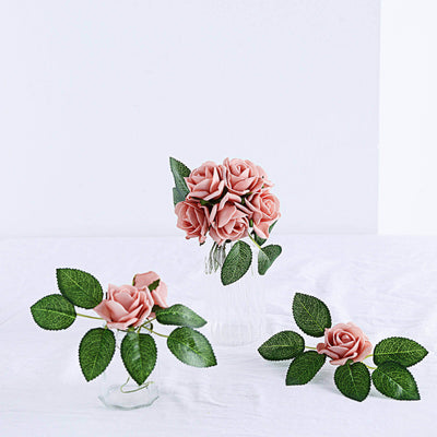 Pink artificial roses in a glass vase with leaves, studio shot.