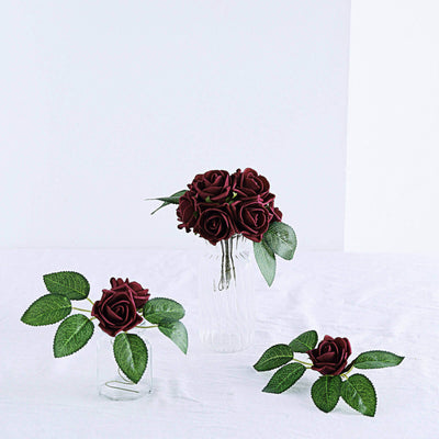 Red artificial roses in clear glass vases with green leaves.